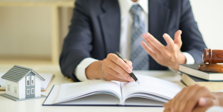 Businessman in a suit holding a pen and discussing paperwork, implying consulting, advisory, or client services.
